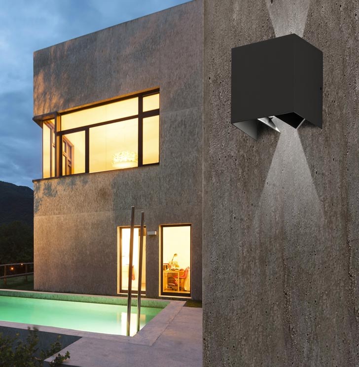 Applique LED murale noire extérieure éclairant un mur en béton d'une villa